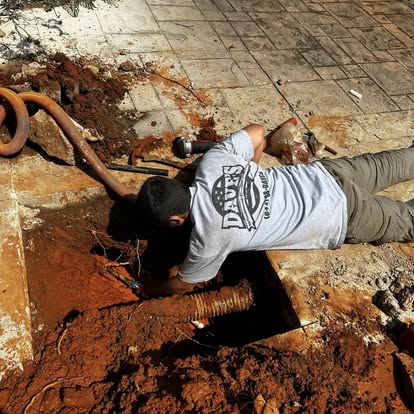 Plumbing technician reaching into an access hole during slab leak or underground plumbing repair